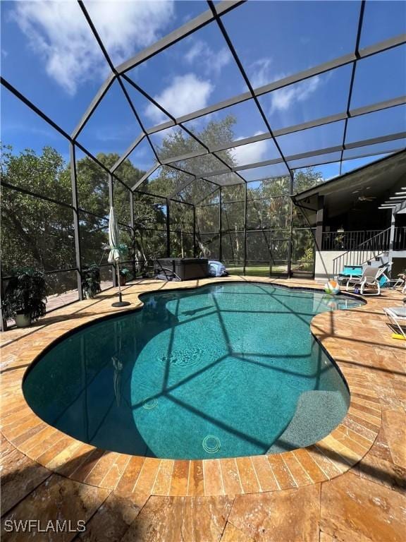 view of pool with glass enclosure and a patio area