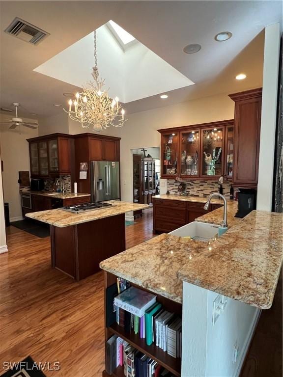 kitchen featuring kitchen peninsula, appliances with stainless steel finishes, backsplash, and a kitchen island