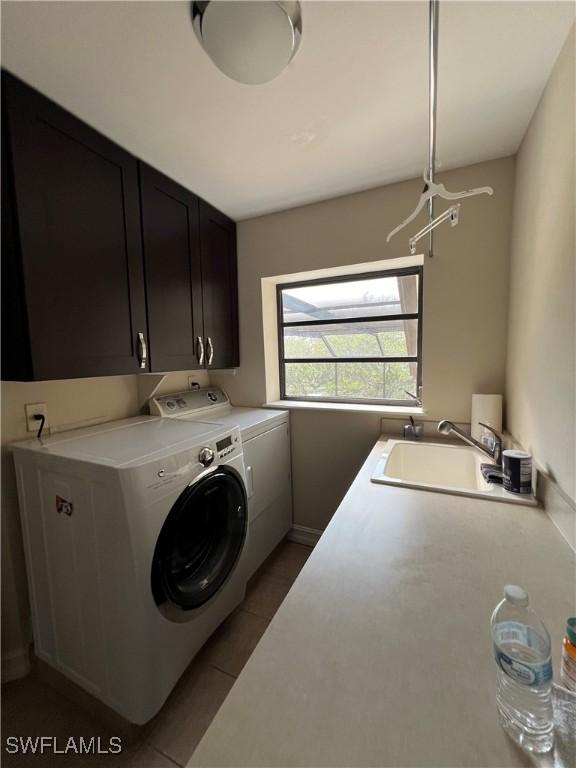 clothes washing area featuring tile patterned flooring, cabinets, sink, and washing machine and dryer