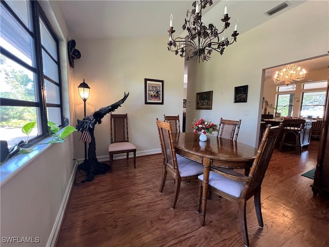 dining area with dark hardwood / wood-style flooring, a healthy amount of sunlight, and an inviting chandelier