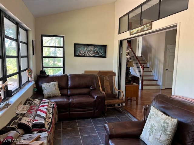 living room featuring lofted ceiling, dark tile patterned flooring, and stairway