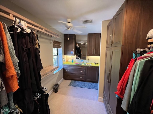 walk in closet with a ceiling fan, visible vents, and light carpet