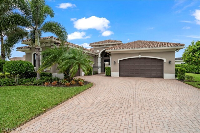 4365 Caldera Cir, Naples, FL 34119 - mediterranean / spanish home featuring decorative driveway, an attached garage, stucco siding, and a front yard