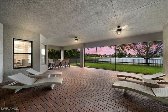 patio terrace at dusk with a yard and ceiling fan