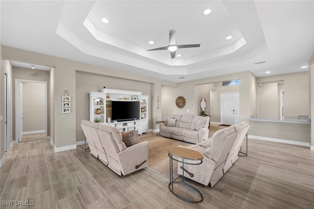 living room featuring a raised ceiling and ceiling fan