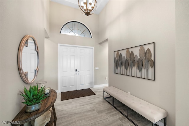 foyer entrance with a notable chandelier, a towering ceiling, and light wood-type flooring