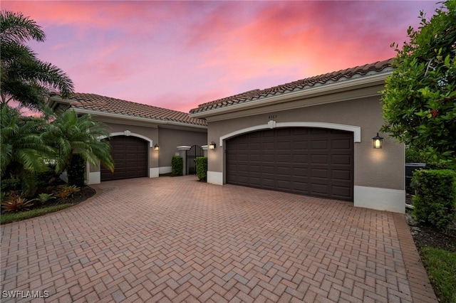 4365 Caldera Cir, Naples, FL 34119 - mediterranean / spanish-style home with stucco siding, decorative driveway, a garage, and a tiled roof
