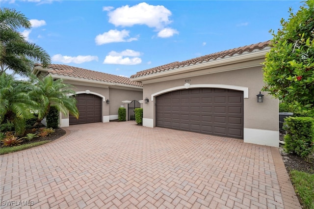 4365 Caldera Cir, Naples, FL 34119 - mediterranean / spanish house with stucco siding, decorative driveway, a tiled roof, and an attached garage