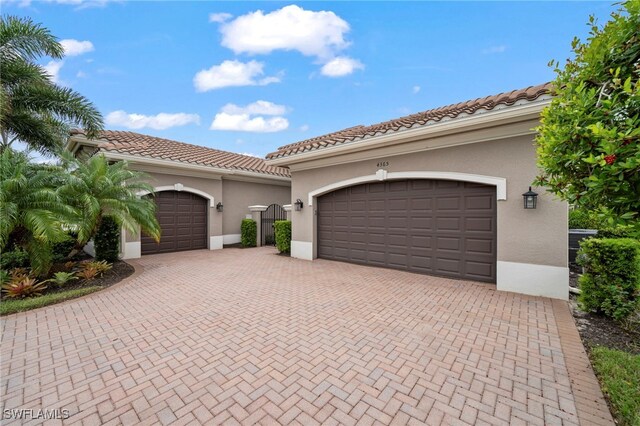 4365 Caldera Cir, Naples, FL 34119 - mediterranean / spanish-style home featuring stucco siding, decorative driveway, a tile roof, and an attached garage