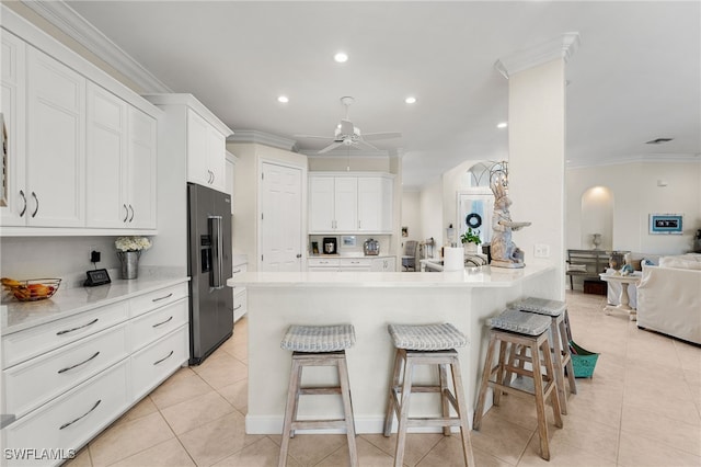 kitchen with white cabinetry, crown molding, a breakfast bar area, and high quality fridge