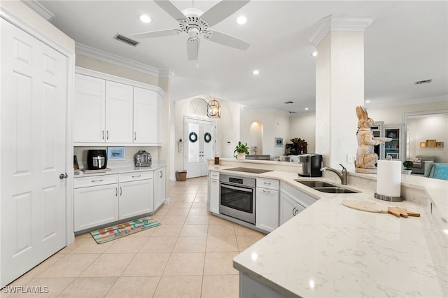 kitchen with sink, ornamental molding, light stone countertops, white cabinets, and oven