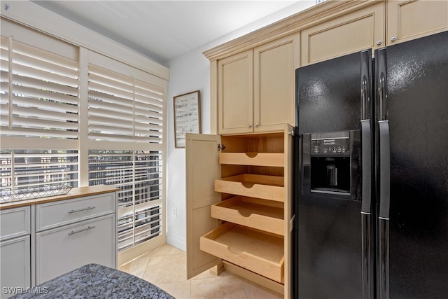 kitchen featuring light tile patterned floors, cream cabinets, and black refrigerator with ice dispenser