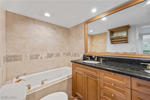 bathroom featuring vanity, tile walls, tiled tub, and toilet