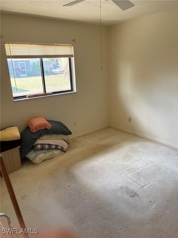 empty room featuring ceiling fan and light carpet