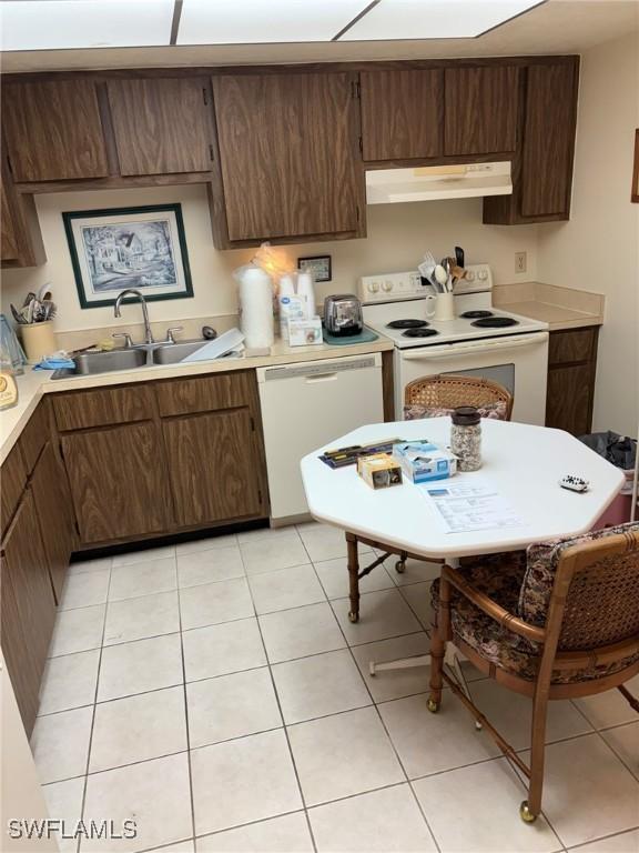 kitchen with sink, white appliances, dark brown cabinets, and light tile patterned flooring