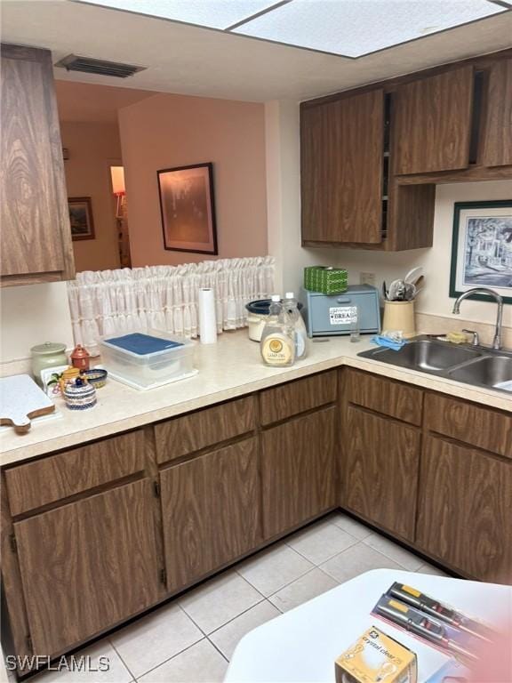 kitchen with light tile patterned flooring, sink, and dark brown cabinets