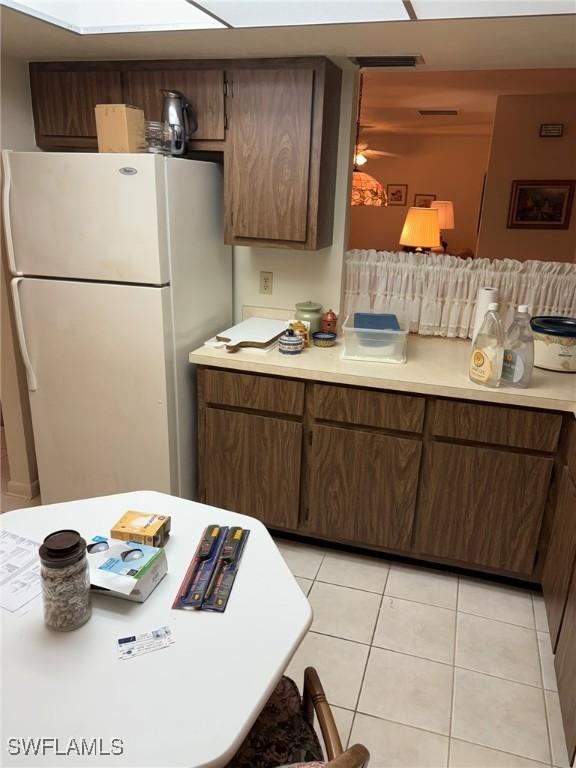 kitchen featuring white refrigerator, dark brown cabinets, and light tile patterned floors