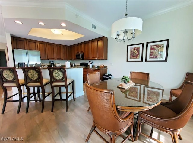 dining space with light hardwood / wood-style floors, a chandelier, and ornamental molding