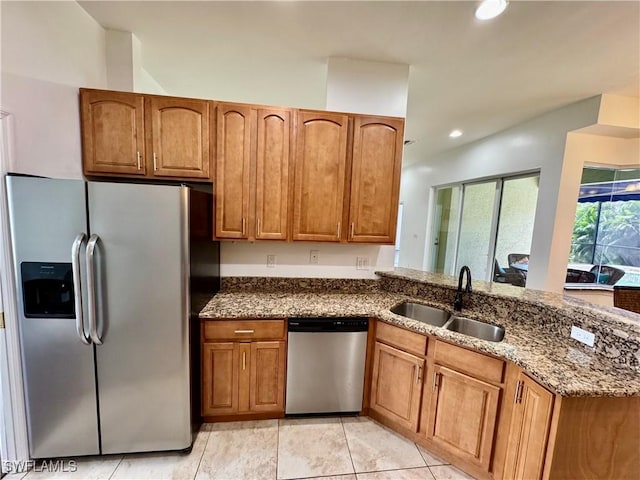 kitchen with sink, kitchen peninsula, dark stone countertops, light tile patterned floors, and appliances with stainless steel finishes