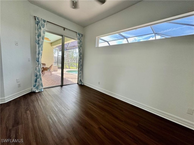 unfurnished room featuring a healthy amount of sunlight, ceiling fan, and dark wood-type flooring