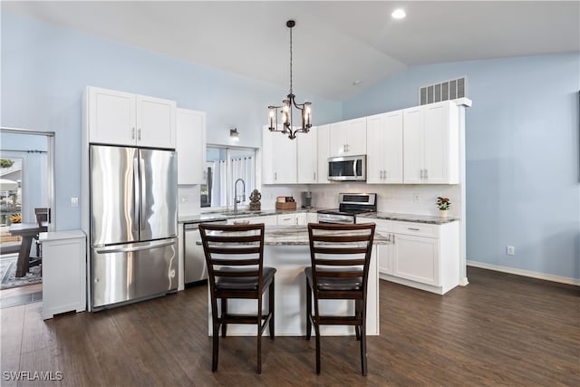 kitchen featuring dark hardwood / wood-style flooring, a center island, stainless steel appliances, and vaulted ceiling