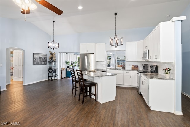 kitchen featuring dark wood-type flooring, a center island, appliances with stainless steel finishes, and vaulted ceiling