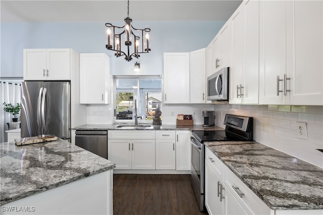 kitchen featuring hanging light fixtures, dark stone counters, sink, white cabinetry, and appliances with stainless steel finishes