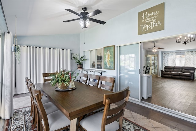 dining area with hardwood / wood-style flooring, ceiling fan with notable chandelier, and vaulted ceiling