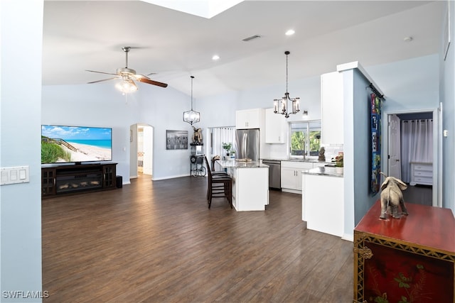 kitchen with lofted ceiling, white cabinets, a breakfast bar area, appliances with stainless steel finishes, and a kitchen island