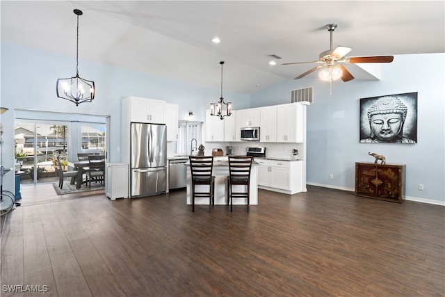 kitchen featuring a breakfast bar area, appliances with stainless steel finishes, white cabinetry, dark wood-type flooring, and a center island