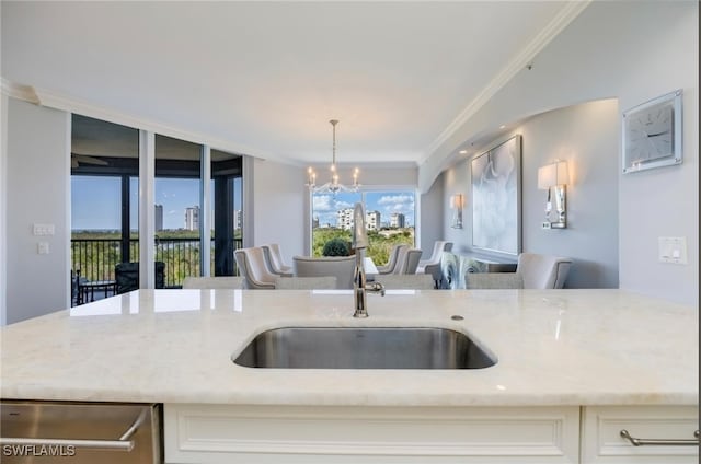 kitchen with light stone countertops, sink, hanging light fixtures, a notable chandelier, and ornamental molding