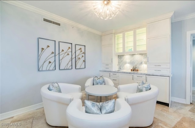 living area with crown molding and an inviting chandelier