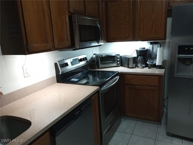 kitchen with stainless steel appliances, dark brown cabinets, and light tile patterned floors