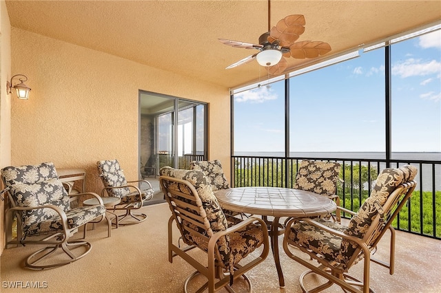 sunroom / solarium featuring ceiling fan and a water view