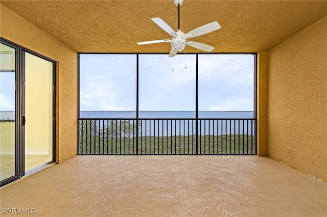 unfurnished sunroom with a wealth of natural light, a water view, and ceiling fan