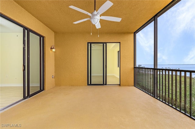 unfurnished sunroom with ceiling fan and a water view