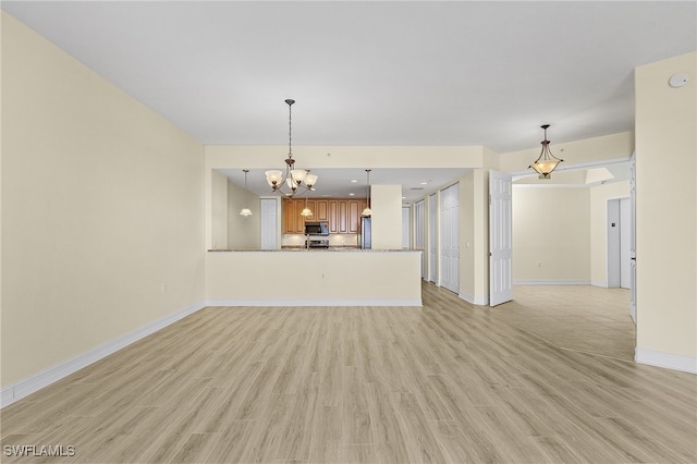 unfurnished living room featuring an inviting chandelier and light wood-type flooring