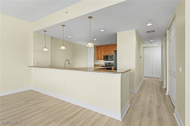 kitchen with kitchen peninsula, light stone countertops, stainless steel appliances, and decorative light fixtures