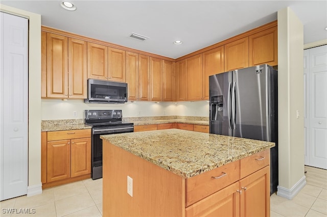 kitchen featuring a center island, light stone counters, stainless steel appliances, and light tile patterned flooring