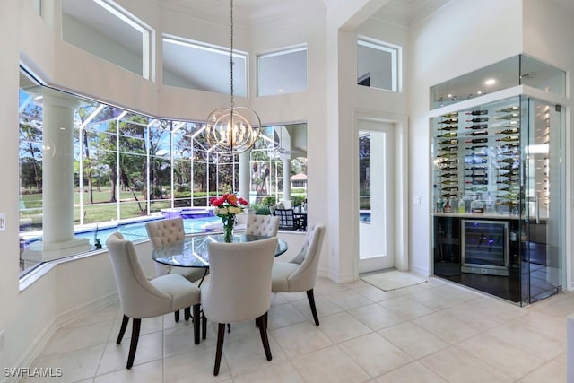 dining room with an inviting chandelier, tile patterned flooring, a high ceiling, and crown molding