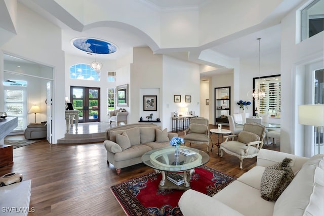 living area with wood finished floors, a towering ceiling, french doors, and an inviting chandelier