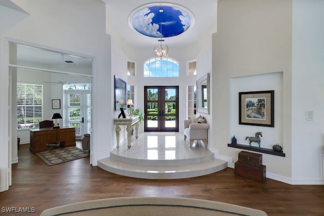 foyer entrance with a high ceiling, wood finished floors, a wealth of natural light, and french doors