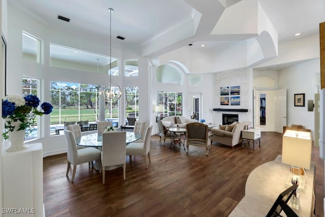 dining area featuring a fireplace, ornamental molding, dark wood-style flooring, and a notable chandelier