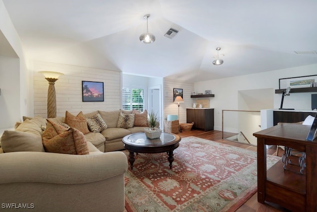 living area featuring lofted ceiling, visible vents, and wood finished floors