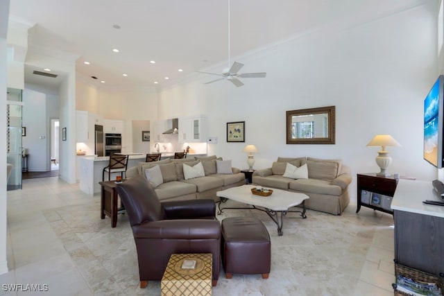 living room with a towering ceiling, ceiling fan, and recessed lighting