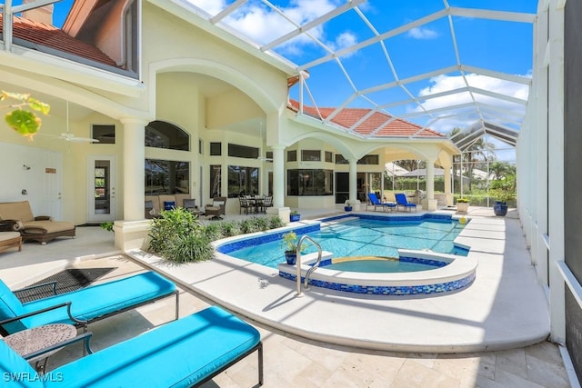 view of swimming pool featuring a ceiling fan, glass enclosure, a pool with connected hot tub, and a patio area