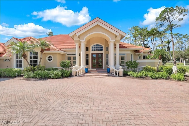 view of front facade featuring stucco siding, a tiled roof, and french doors