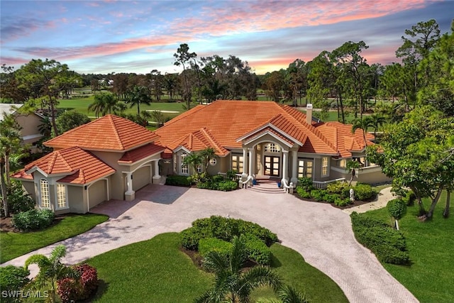 view of front facade featuring driveway, a tile roof, an attached garage, and french doors