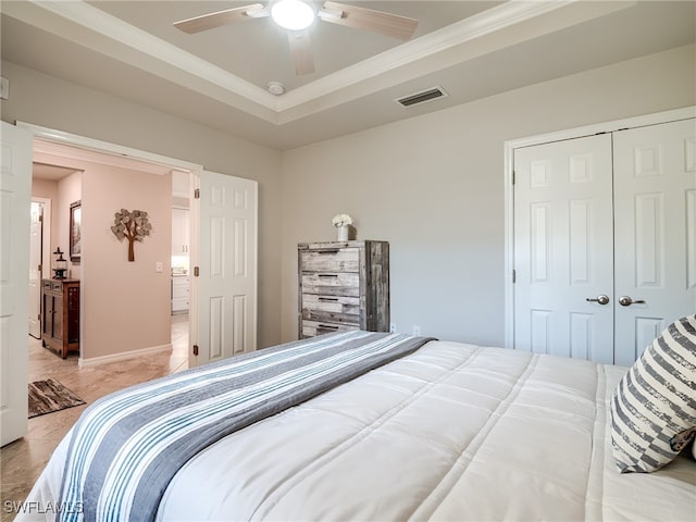 bedroom with a tray ceiling, a closet, crown molding, and ceiling fan