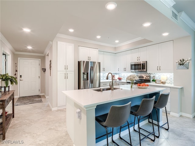 kitchen featuring appliances with stainless steel finishes, a kitchen breakfast bar, a kitchen island with sink, sink, and white cabinets